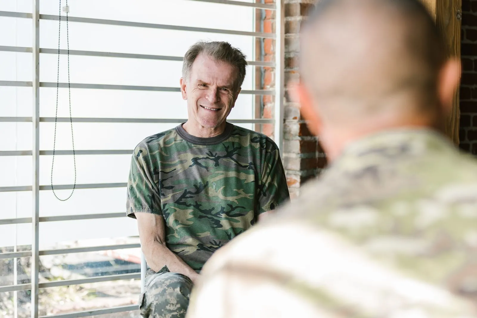 Senior and fellow military veterans engaging in a supportive therapy session indoors.